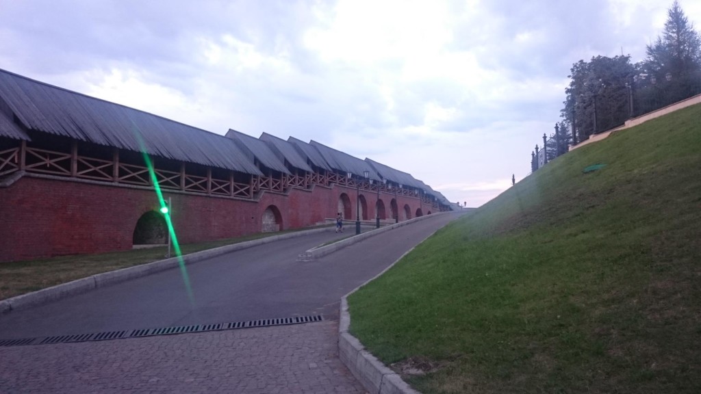 Mauer des Kremlins von Kasan, davor eine Straße und eine Wiese. Ein grünes Ampellicht