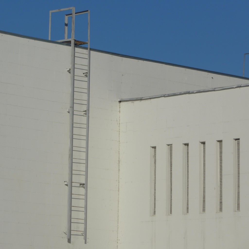 Eine Leiter und sehr schmale Fenster an einer weißen Fassade